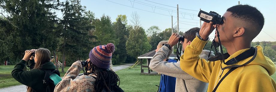 Using materials from Ontario Nature’s birding backpacks, early morning birders turn their binoculars to observe warblers