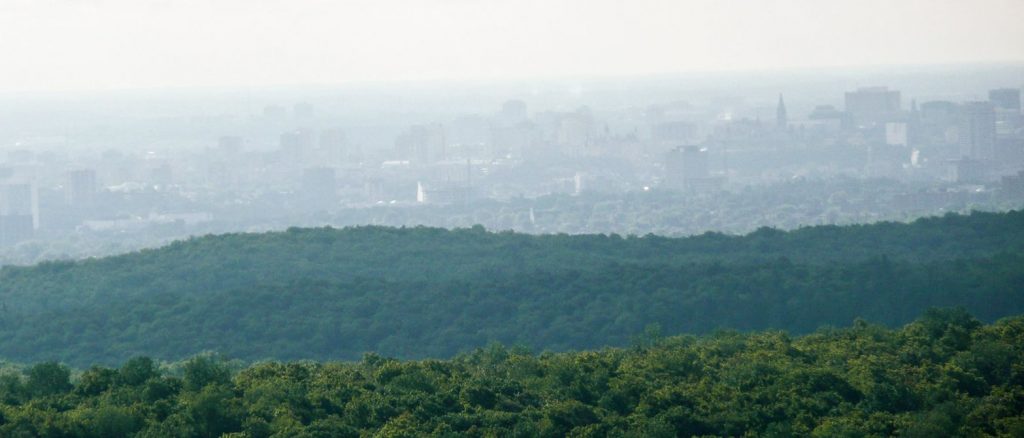 View of Ottawa from Gatineau Park, view above forested hills overlooking dense buildings in a busy city, National Park