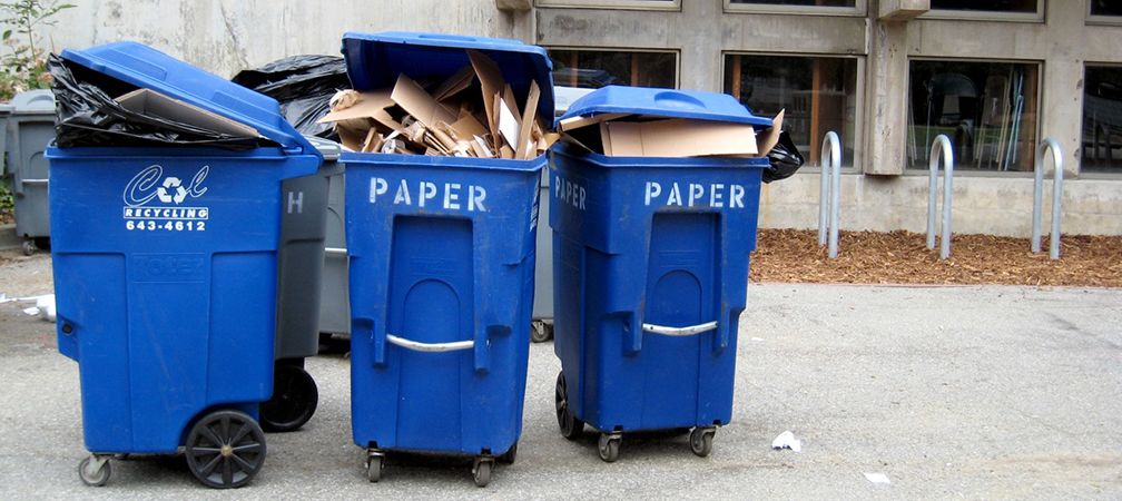 Recycling bins overloaded with recyclable paper with materials